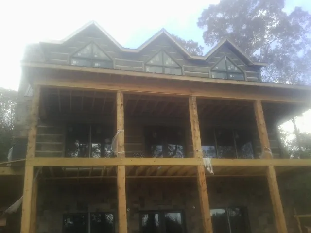 Dormers and porch framing on a large log home under construction — Roof Coating work by our crew in Montverde