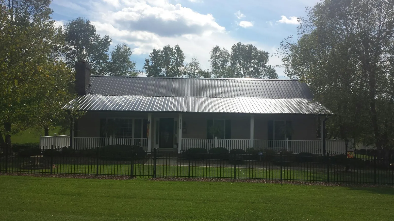Gray metal roof on a brick ranch with a full width front porch — Gutter Guard Installation work by our crew in Montverde