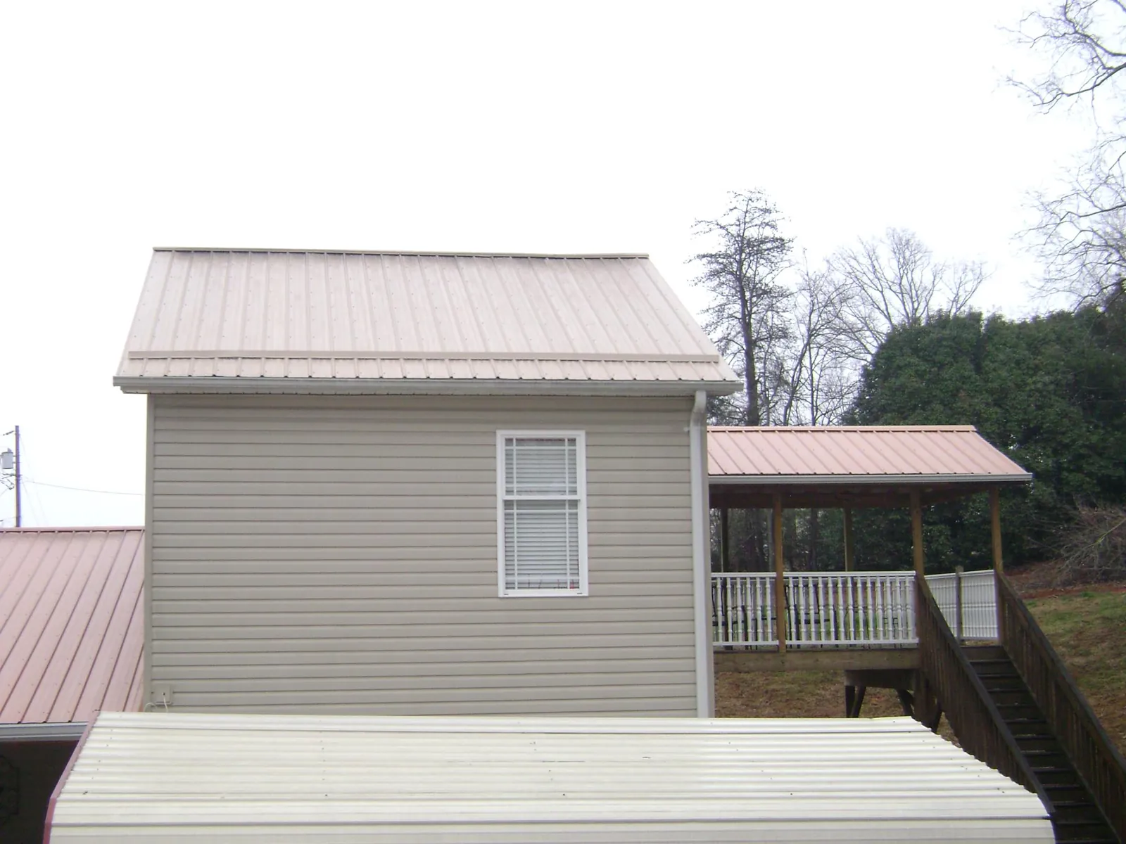 Tan metal roofs on a two story addition and attached porch, from a Roof Replacement job in Montverde