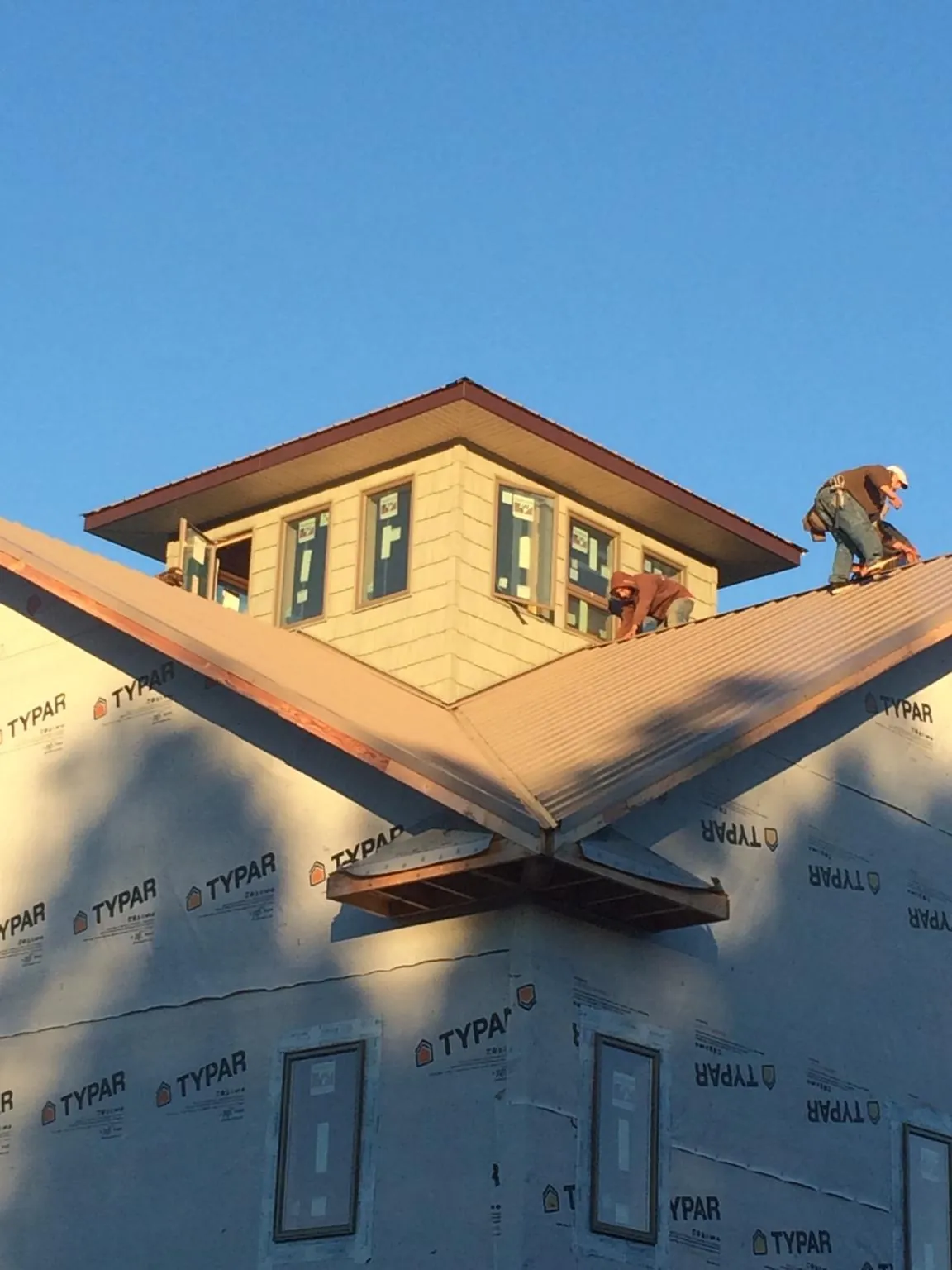 Roofers working around a rooftop cupola on a new metal roof at sunset — Roof Waterproofing in Montverde by Roofing Brothers